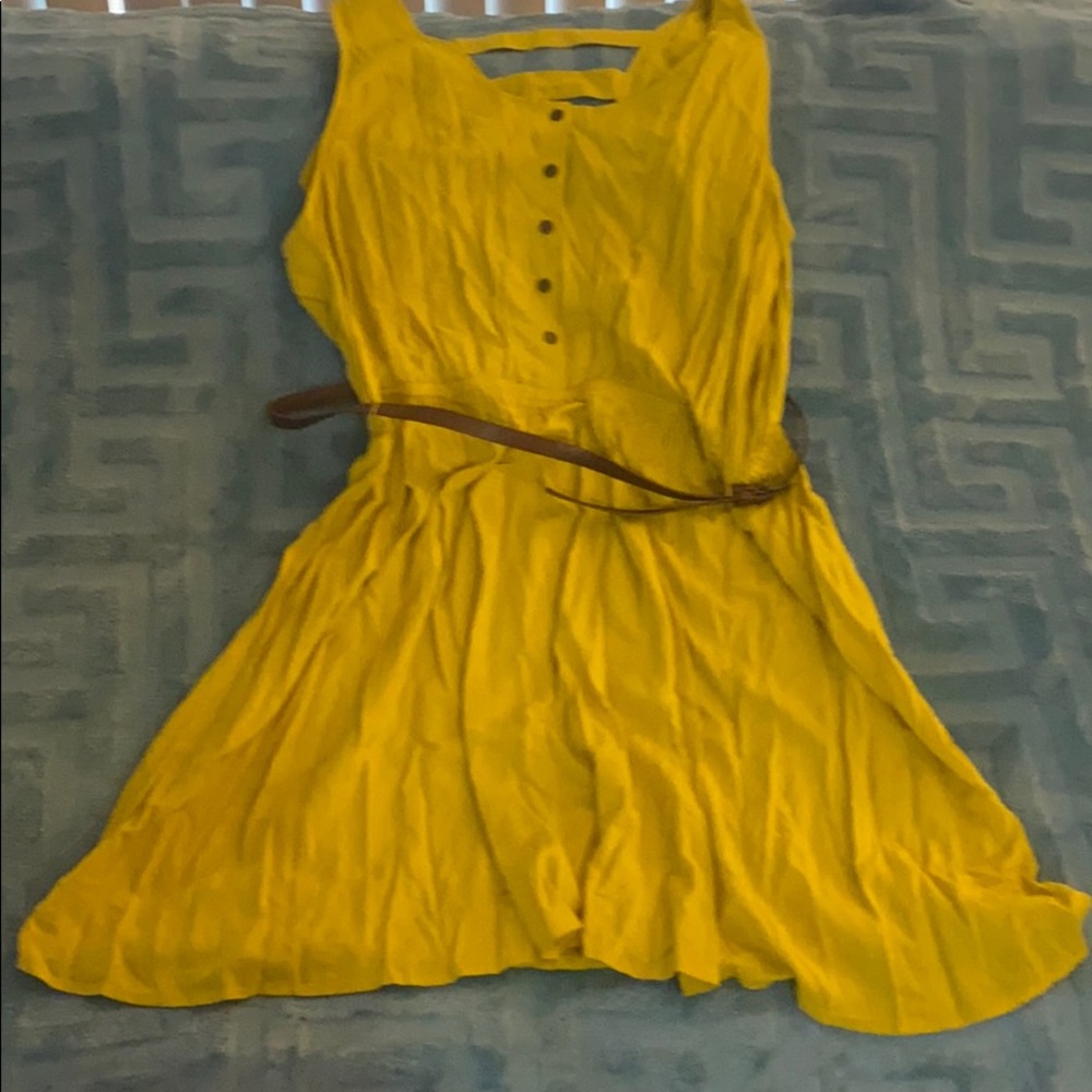 Gold sleeveless dress with brown belt .
